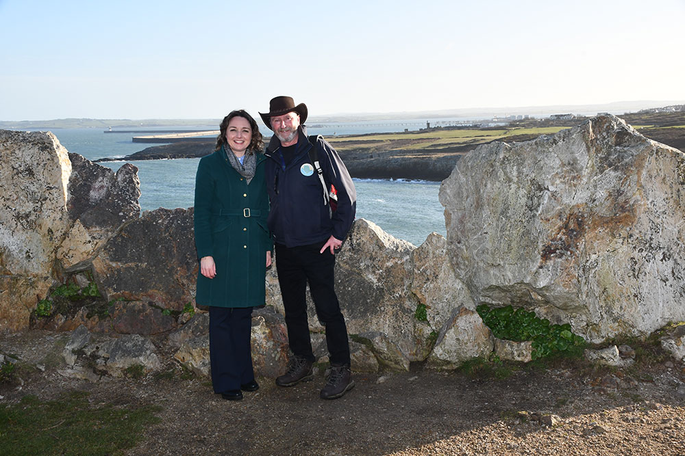 Two people with Holyhead Breakwater in the background